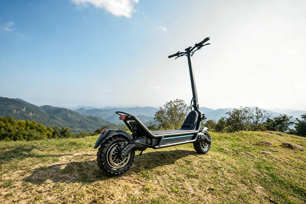 Off-road capable commuter electric scooter displayed on scenic mountain overlook with clear blue sky
