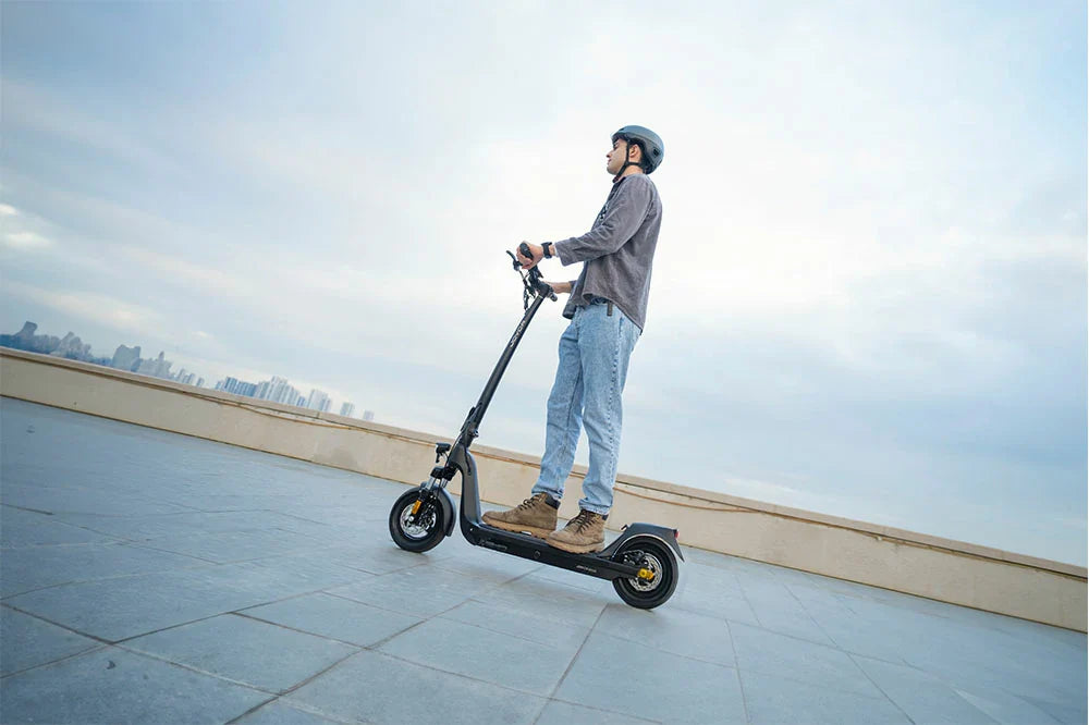 Casual rider wearing helmet riding compact commuter electric scooter on rooftop observation deck